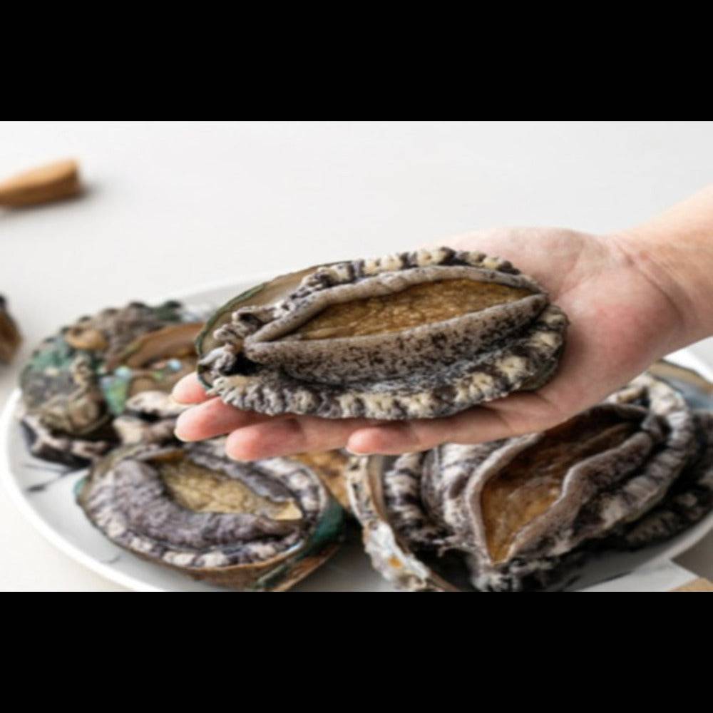 a person holding a plate with abalone on it